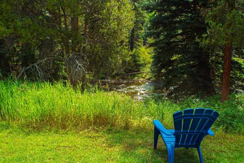 a blue chair sitting in the grass next to a stream at Spruce Creekside in Vail