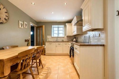 a kitchen with a large wooden table and a kitchen with white cabinets at Lapwing Cottage Docking in Docking