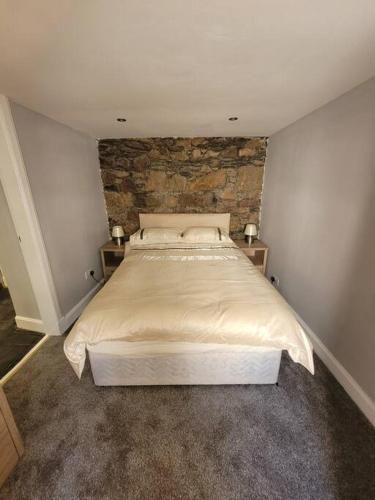 a bedroom with a large bed with a brick wall at 2 Kilkerran Road in Campbeltown