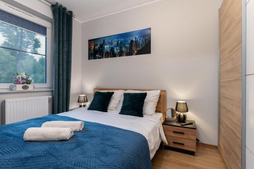 a bedroom with a blue and white bed and a window at Apartament Sowa Deluxe in Bielsko-Biala