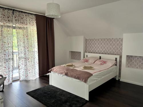 a bedroom with a large bed and a large window at Forest Lux in TÄƒuÅ£ii MÄƒgheruÅŸ