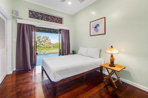 a bedroom with a bed and a table with a lamp at The Aloha Villa - 30-Night Minimum in Honokaa