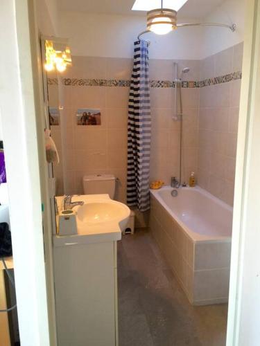 une salle de bain avec un lavabo, une baignoire et des toilettes dans l'établissement Appartement côte des basques, à Biarritz