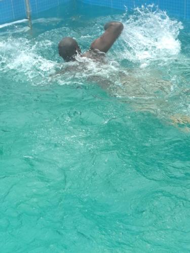 a person laying in the water in a swimming pool at Dreamers Lodge in Prampram
