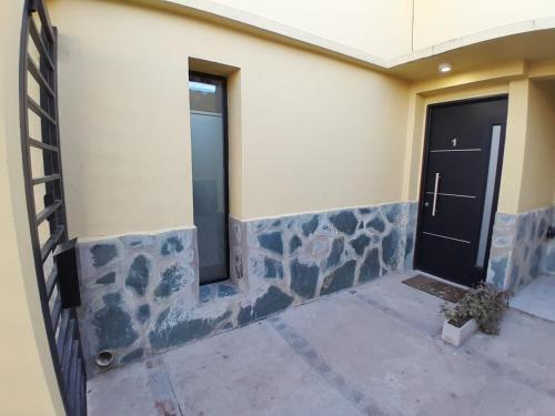 a building with two doors and a stone wall at TresA -1- in Tres Arroyos