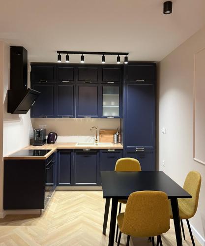 a kitchen with blue cabinets and a table and chairs at APARTAMENT DISCReeT SLeeP iN CITY CENTER PARKING GARAŻ KOZIA KIELCE in Kielce