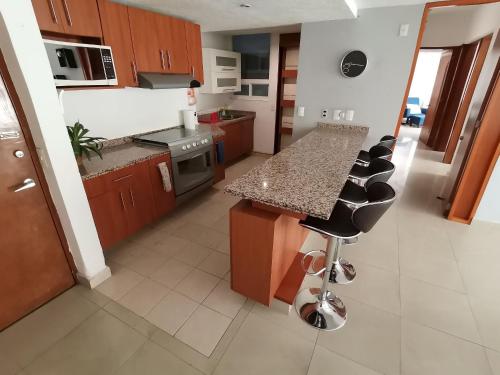 a kitchen with brown cabinets and a counter with bar stools at Amplio y Moderno en Antara, Carso y Embajada EEUU in Mexico City