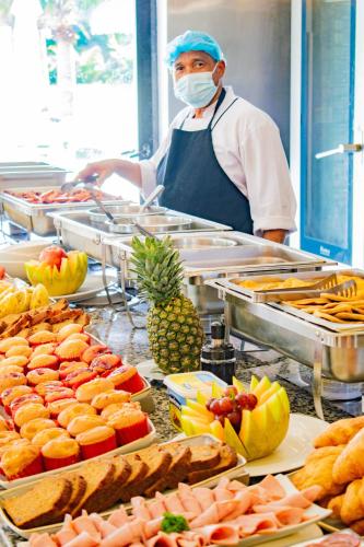a chef wearing a face mask in a kitchen with food at Playa Palmera Beach Resort in Punta Cana