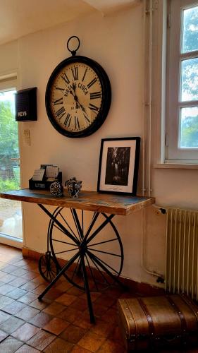 a clock hanging on the wall above a table at Gite des Trévignes in Cambremer