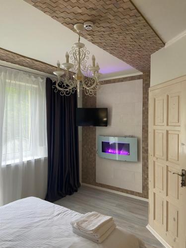 a bedroom with a chandelier and a tv on a wall at Hotel Tys in Dilove