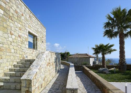 a stone building with stairs and a palm tree at Anaxo Resort in Riglia