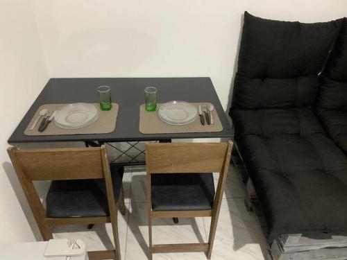 a table with two plates and two chairs and a couch at Loft moderno próximo Aeroporto e UPF in Passo Fundo