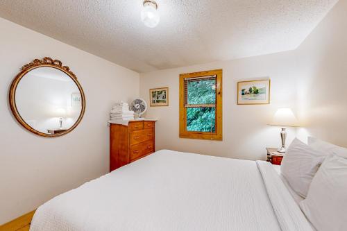 een slaapkamer met een wit bed en een spiegel bij Pine Knoll on Lake George 