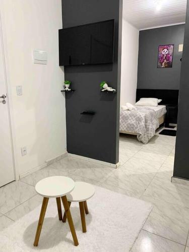 a room with two tables and a tv and a bed at Loft Mobiliado com Cama de Casal e Solteiro in Passo Fundo