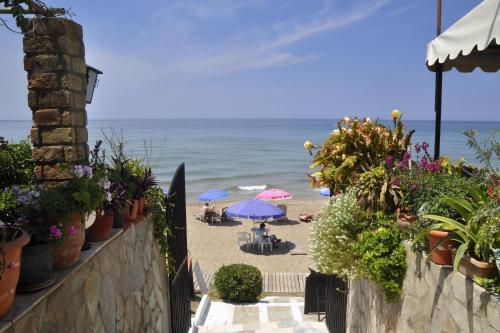 a beach with umbrellas and people sitting on the sand at Dandidis Seaside Pension in Agios Gordios