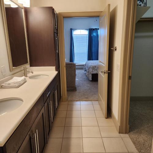 a bathroom with two sinks and a door to a bedroom at Domain at Kirby in Houston