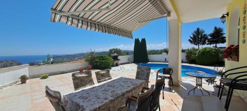 un patio con mesa, sillas y piscina en Villa Byala Grape House en Byala