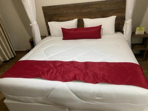 ein großes weißes Bett mit einem roten Kissen darauf in der Unterkunft The ParkHome in Nairobi