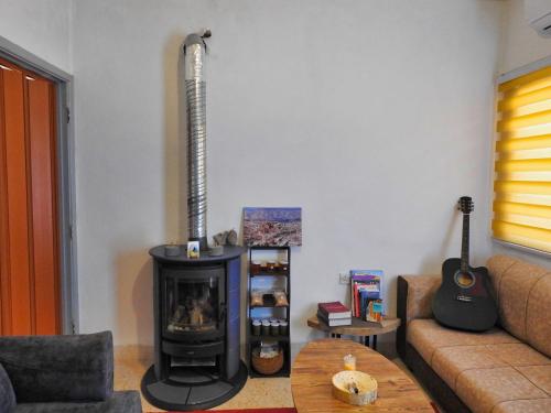 a living room with a stove and a guitar on the wall at Beit Philodemus in Um Qeis