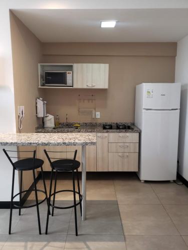 cocina con mesa, 2 sillas y nevera en Spot Residence São Carlos 700m da USP, en São Carlos