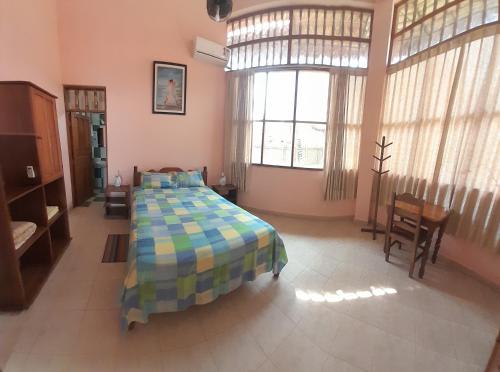 a bedroom with a bed in a room with windows at La Isla de los Tucanes in Rurrenabaque