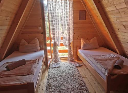 two beds in a wooden room with a window at Konak kod Tose in Banja Luka