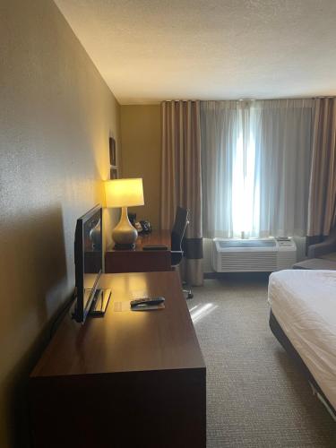 a hotel room with a bed and a desk with a television at Comfort Inn Ellensburg in Ellensburg