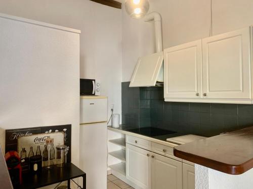 La cuisine est équipée de placards blancs et d'un réfrigérateur blanc. dans l'établissement Le Cosy de la Vieille Intendance, à Perpignan