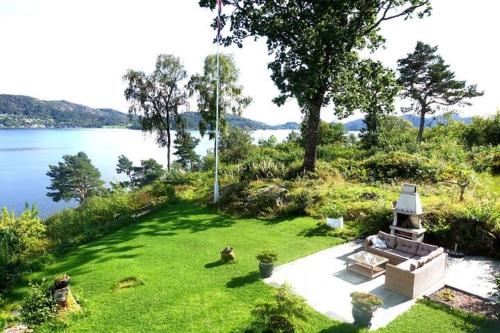 a garden with a bench in the grass next to the water at Villa Arboretet - Seaside villa with private pool & infrared sauna in the heart of Arboretet, Bergen in Bergen