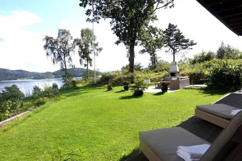 a green yard with a view of the water at Villa Arboretet - Seaside villa with private pool & infrared sauna in the heart of Arboretet, Bergen in Bergen