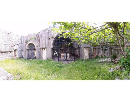 an old stone building with a gate in a yard at Ratac Eco Guest House in Sutomore