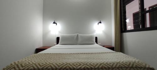 um quarto com uma cama com duas luzes em HOTEL BUGANVILIA em Oiba
