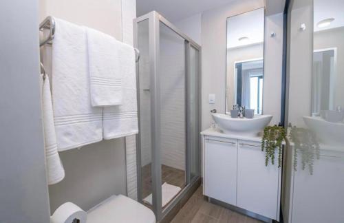 a white bathroom with a sink and a mirror at The Regency Cosy Apartment- 419 in Pretoria
