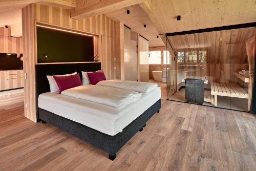 a bedroom with a large bed and a bathroom at Staufen Chalets am Schlossberg in Oberstaufen