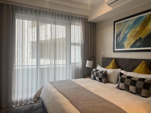 a bedroom with a bed and a large window at The Regency Cosy Apartment- 419 in Pretoria