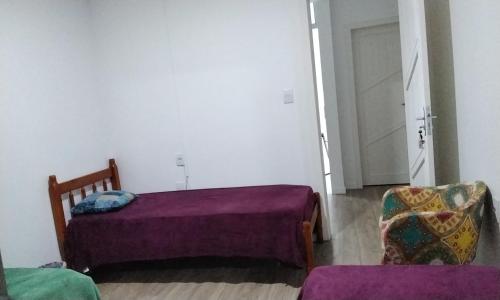 1 dormitorio con 1 cama, 1 silla y 1 puerta en Tenda Caiu do Céu, en Osório