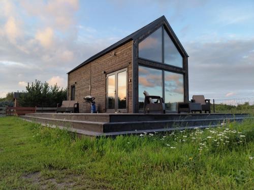 mały dom ze szklanymi oknami na polu w obiekcie Your Private Hytte w Smołdzinie