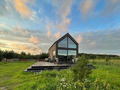 a glass house on a wooden deck in a field at Your Private Hytte in Smołdzino