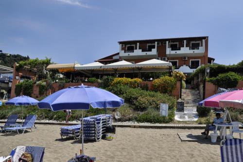 a beach with chairs and umbrellas on the sand at Dandidis Seaside Pension in Agios Gordios