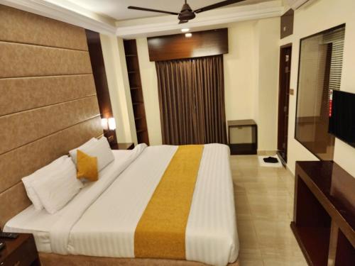 a bedroom with a large bed and a television at White Park Hotel & Suites in Chittagong