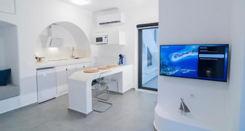 eine weiße Küche mit einer Theke und einem TV an der Wand in der Unterkunft Shape-Spiral in Kalymnos