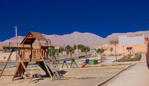 um parque infantil com uma estrutura de jogos de madeira no deserto em HÔTE SAHARA em Goulmima