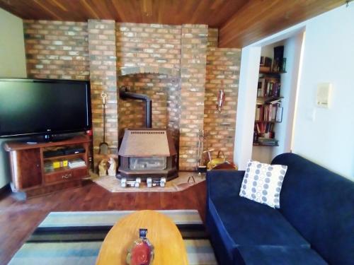 a living room with a fireplace with a tv and a couch at Hannie's Gasthuis in Blind Bay