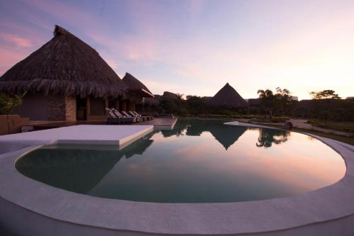 a pool at a resort with a sunset in the background at Waka Wená in Santa Elena de Uairén