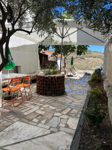 a patio with a table and chairs and an umbrella at Casa da Avó Maria, Largo de Santo António, n 97395AL in Freixo de Espada à Cinta