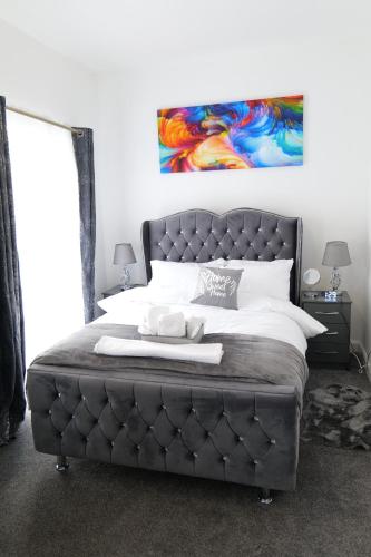 a bedroom with a large bed with a large headboard at Milton Keynes Love Home in Bletchley