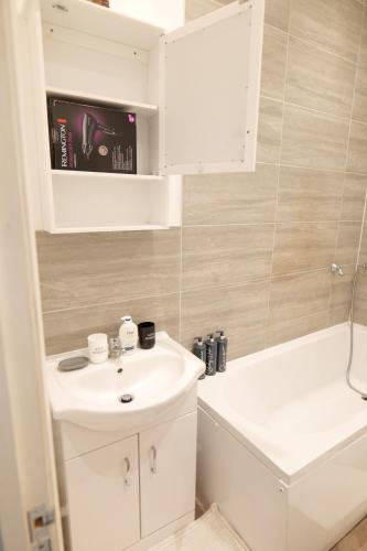 ein Badezimmer mit einem weißen Waschbecken und einer Badewanne in der Unterkunft Milton Keynes Love Home in Bletchley