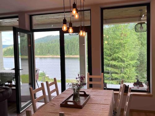 a dining room with a table and a view of a lake at Nook by the lake Dealu Botii in Dealu Botii