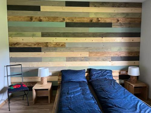 a bed in a room with a wooden wall at Nook by the lake Dealu Botii in Dealu Botii