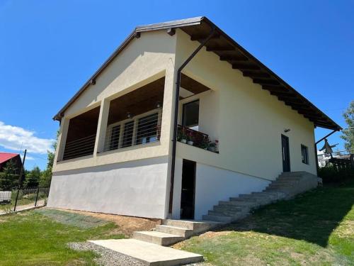 a small white house with a porch and stairs at Nook by the lake Dealu Botii in Dealu Botii